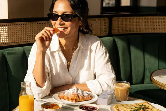 routine.webpWoman placing a BIOSTRIPS oral dissolving strip on her tongue before breakfast at a café table with croissant and coffee