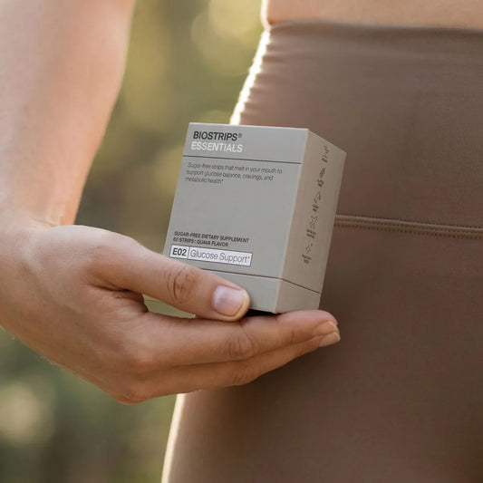 Adult holding an HSA or FSA debit card in one hand and a BIOSTRIPS Glucose Support strip in the other