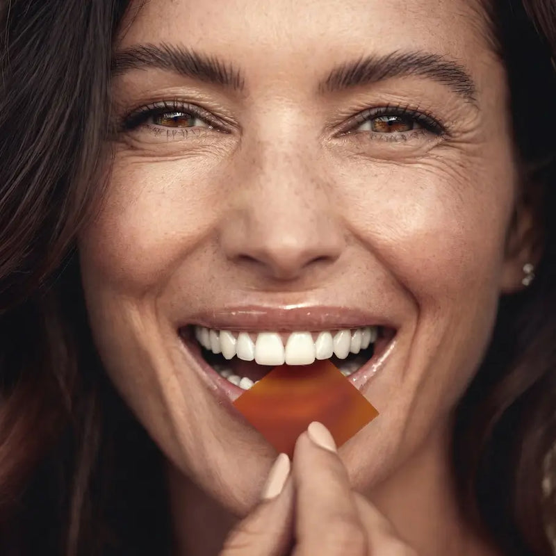 A woman holding a nutrient strips close to her mouth