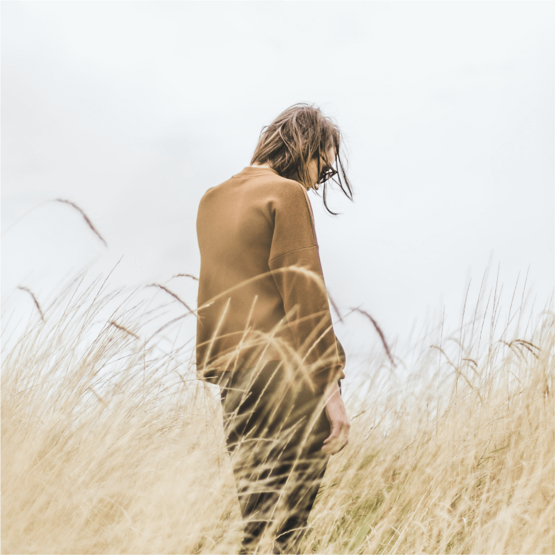 person standing in long yellow grass in nature