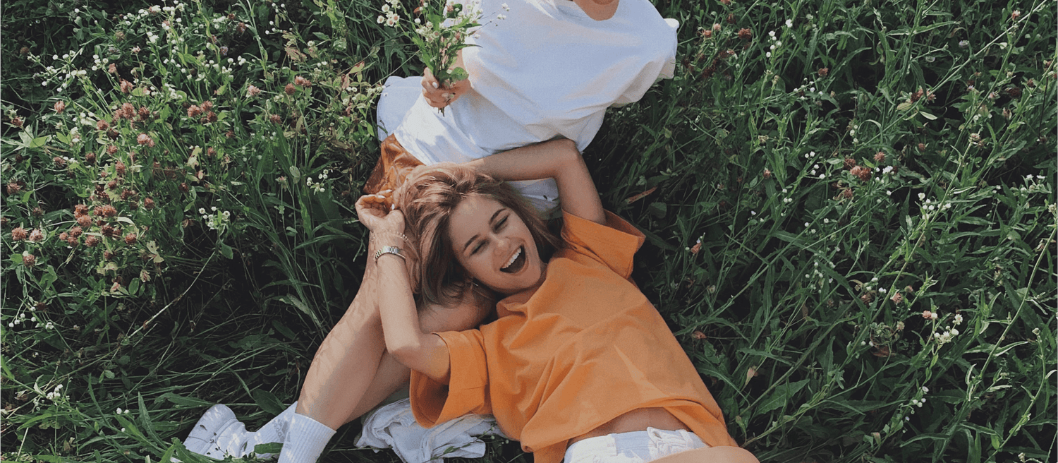 two healthy and happy friends lying in the grass